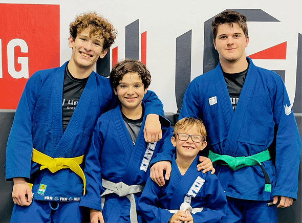 United Grappling Club youth students smiling together in Brazilian jiu-jitsu gis