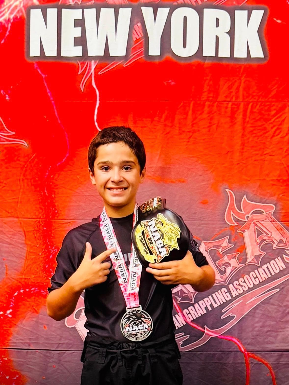 A young United Grappling Club competitor with a medal and championship belt